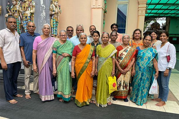 Community members gathering together outside a temple in colourful traditional dress