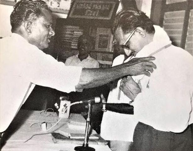 An archived black-and-white photograph of a ceremonial presentation from the story of Mr. Chinnasamy Rajoo