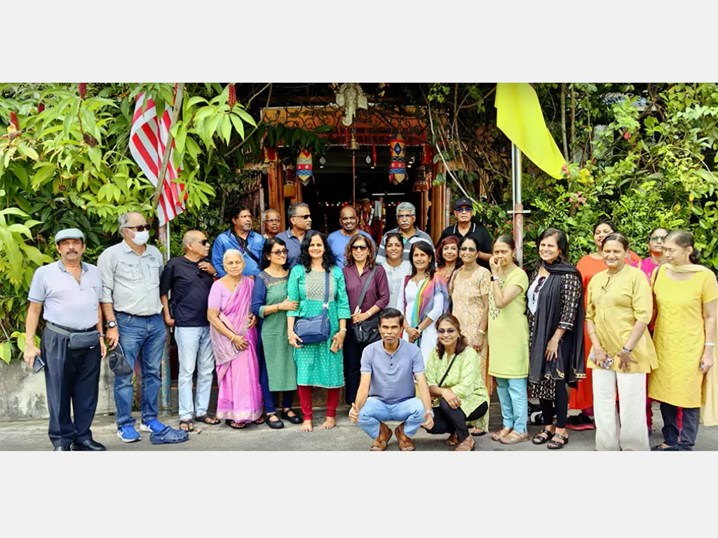 Sangam members gathered for a group photograph at a temple entrance decorated with flags