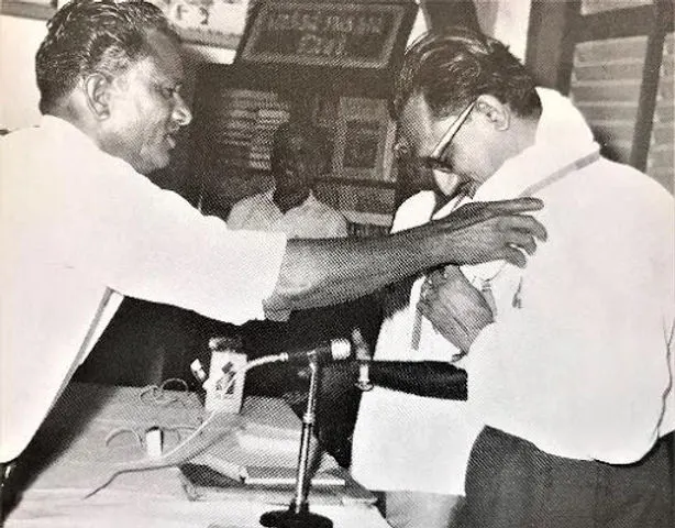 An archived black-and-white photograph of a ceremonial presentation from the story of Mr. Chinnasamy Rajoo